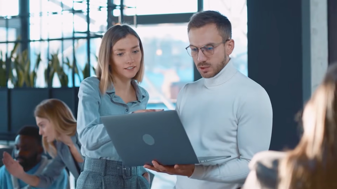 Two travel professionals review agency work on a laptop in an office